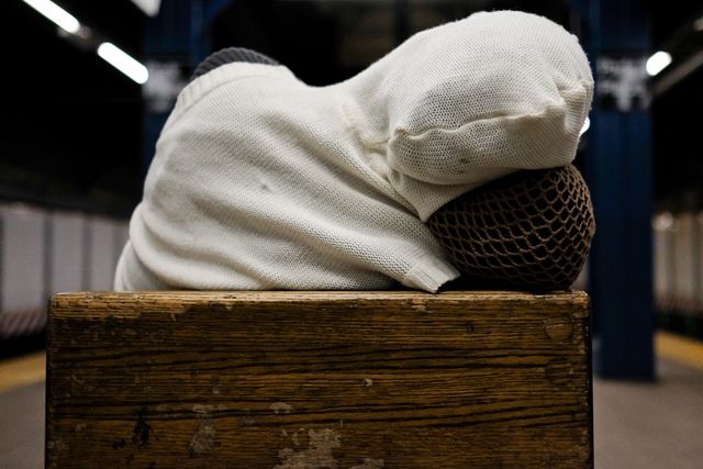 A person rests their head in a NYC subway station.
